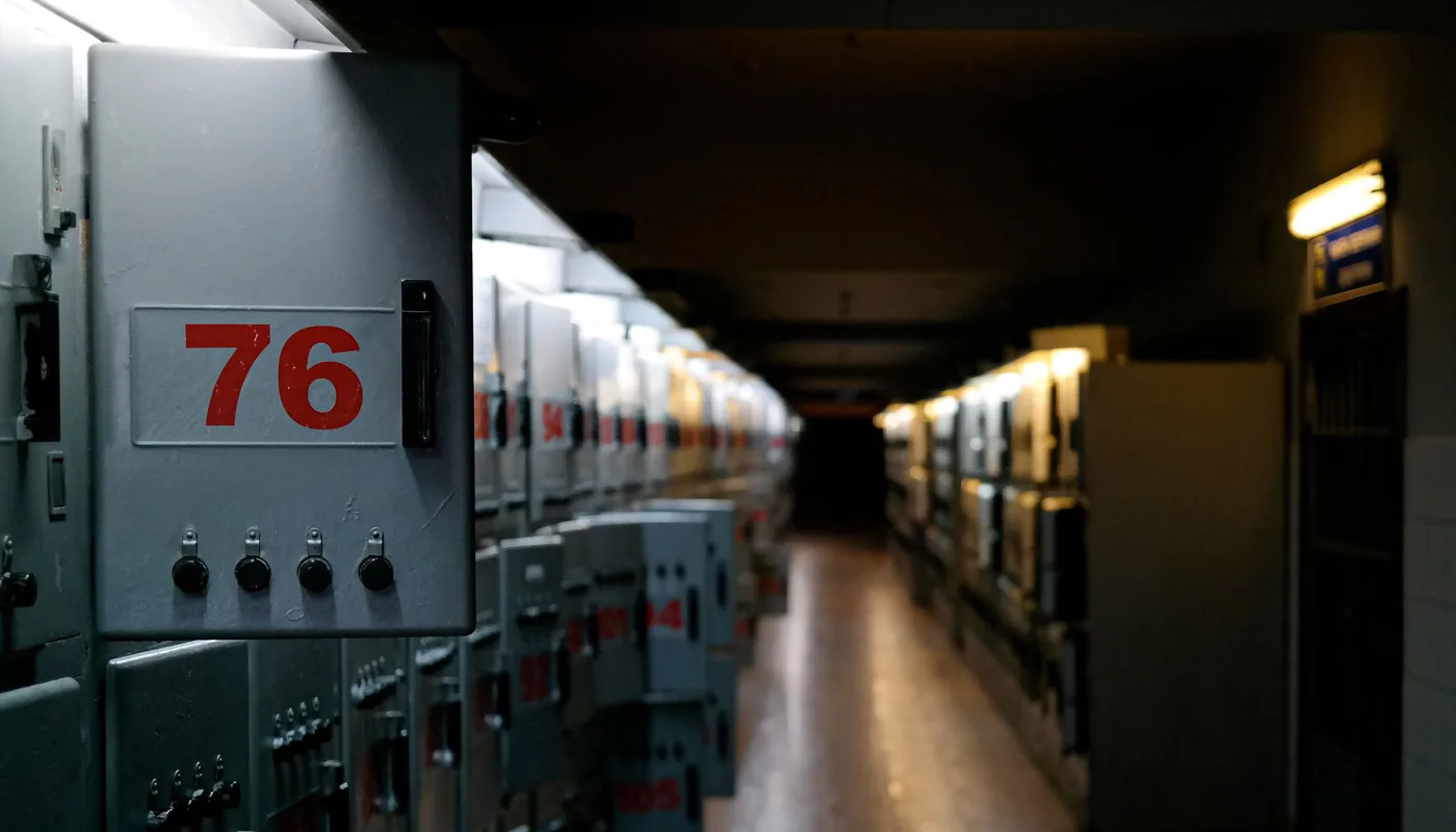 A long corridor lined with numbered grey steel equipment cabinets receding into shadow.