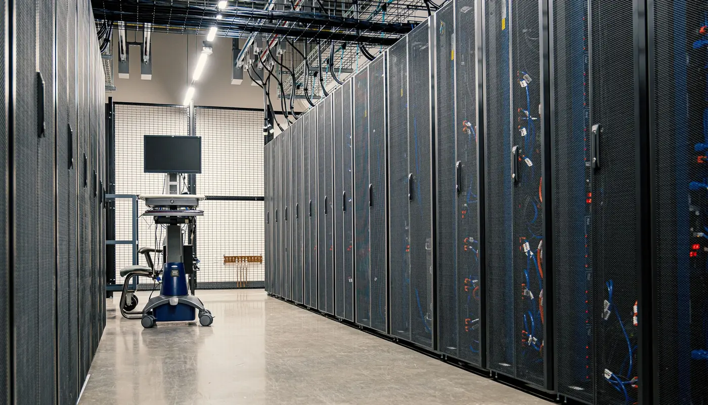 A row of server racks in a data centre aisle with structured cabling running between cabinets.