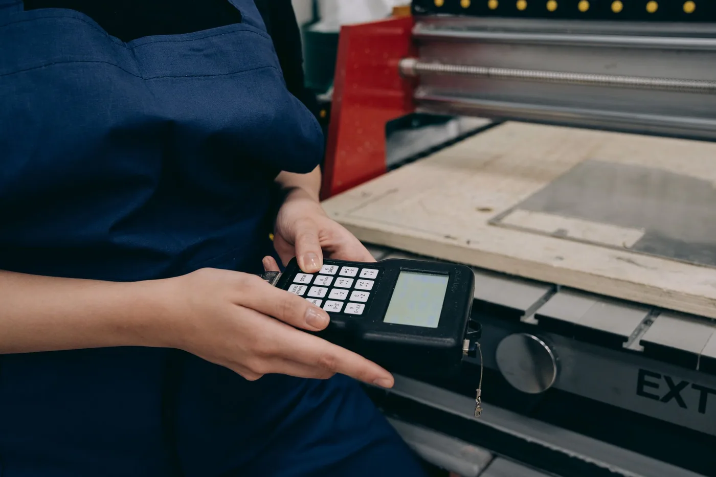 A factory worker operating a touchscreen control panel mounted on a production machine.